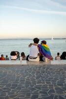 homo paar met regenboog vlag ontspannende Aan promenade in de buurt zee foto