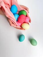handen wieg verzameling van helder gekleurde Pasen eieren in roze kleding stof, oproepen tot thema's van Pasen tradities, familie plezier, en lente ambachten. foto