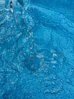 achtergrond dynamisch plons van Doorzichtig water creëren wervelende Golf in blauw water met druppels geschorst in beweging. schoon water concept. foto