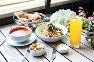 tafel met voedsel kommen en glas van oranje sap foto