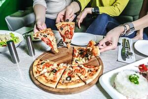 groep van mensen genieten van pizza Bij een tafel foto