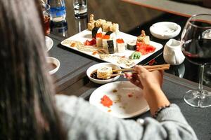 vrouw zittend Bij tafel met bord van sushi foto