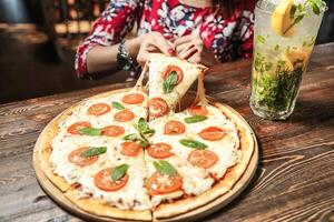 vrouw zittend Bij tafel genieten van een plak van pizza foto