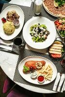 tafel versierd met borden van voedsel en drankjes voor een feestelijk maaltijd. foto