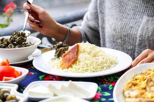 vrouw zittend Bij tafel met borden van voedsel in restaurant foto