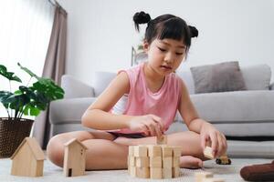 een jong meisje is spelen met houten blokken Aan de verdieping foto