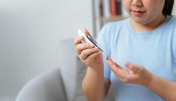 Aziatisch vrouw controle bloed suiker niveau door digitaal glucose meter foto