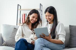 twee Dames zittend Aan een bank, een van hen Holding een tablet foto