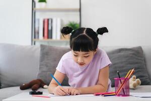 een jong meisje is zittend Aan een bankstel en tekening met kleurpotloden foto