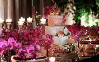geavanceerde roze themed partij met bloemen, snoepgoed, kaarsen en bloemen en gekroond taart foto