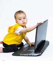 kind spelen met laptop. klein jongen op zoek in computer. foto