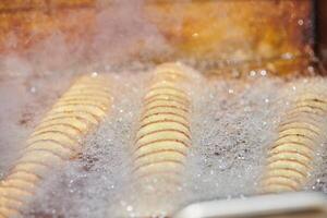 Koken spiraal gebakken aardappel in koken olie, rijk in dik en calorieën snel voedsel, ongezond heerlijk foto