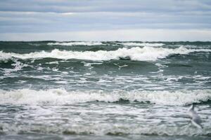 blauwe zee met schuimende golven en bewolkte lucht, zeegezicht foto