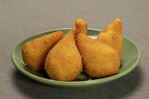 traditioneel gebakken coxinha in bord Aan leisteen achtergrond, populair braziliaans tussendoortje foto