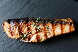 gegrild Zalm vis filet met groen salade Aan de zwart snijdend bord, dichtbij omhoog foto