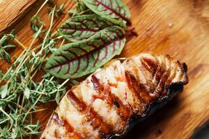 gegrild Zalm vis filet met groen salade Aan de houten snijdend bord, dichtbij omhoog foto