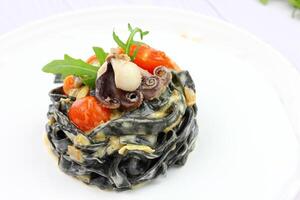 zwart spaghetti. zwart zeevruchten pasta in wit bord Aan zwart achtergrond met kopiëren ruimte. foto
