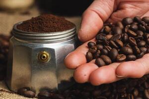 handen Holding geroosterd koffie bonen Aan jute en koffie achtergrond. focus Aan bonen. dichtbij omhoog. foto