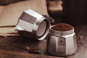 mokka koffie pot gevulde met bruin grond koffie Aan donker houten bord, bereiden naar brouwen Italiaans espresso. foto