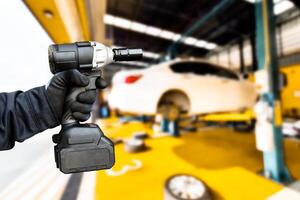 auto reparatie en onderhoud onderhoud concept , hand- van een auto monteur gebruik makend van een draadloos gevolg moersleutel in een auto reparatie faciliteit centrum foto