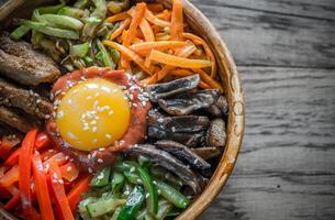 kom van Bibimbap Aan de houten tafel foto