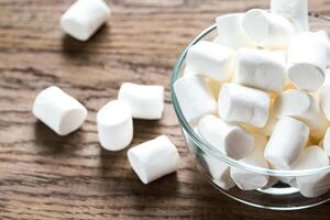 kom van marshmallows Aan de houten achtergrond foto