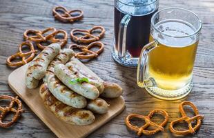 gegrild worstjes met pretzels en mokken van bier foto