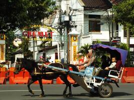 soerakarta, centraal Java, Indonesië april 11, 2024. een paard getrokken vervoer met lokaal toerist voorbijgaan Aan jalan adisucipto in de buurt manahan stadion Bij soerakarta stad, centraal Java, Indonesië foto