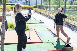 schattig weinig meisje Aan een miniatuur golf Cursus. foto