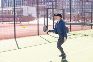 vastbesloten sportief jong vrouw spelen padel in rechtbank foto