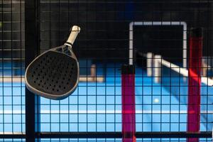 zwart professioneel peddelen tennis racket en bal met natuurlijk verlichting Aan blauw achtergrond. horizontaal sport thema poster, groet kaarten, koppen, website en app foto