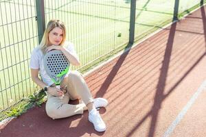 jong sportief vrouw padel speler raken bal met een racket Aan een moeilijk rechtbank foto