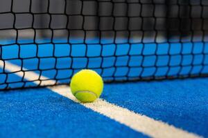 meerdere ballen door de netto Aan een blauw peddelen tennis rechtbank foto