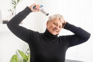 portret van senior vrouw met haar- droger foto