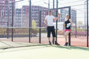 jong vrouw spelen padel tennis met partner in de Open lucht tennis rechtbank foto