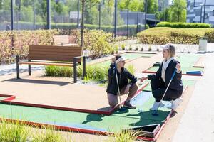 weinig meisje en moeder spelen mini golf foto