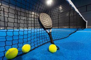 peddelen tennis racket en ballen Aan de blauw peddelen rechtbank foto