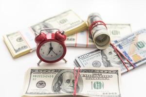een dollar rekeningen Aan een houten tafel met een rood alarm klok in de samenstelling. geld besparing concept. foto
