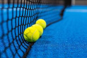 meerdere ballen door de netto Aan een blauw peddelen tennis rechtbank foto