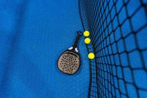 peddelen tennis racket en ballen Aan de blauw peddelen rechtbank foto