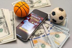 smartphone met het gokken mobiel toepassing en basketbal bal met geld detailopname. sport en wedden concept foto