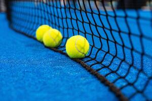 meerdere ballen door de netto Aan een blauw peddelen tennis rechtbank foto