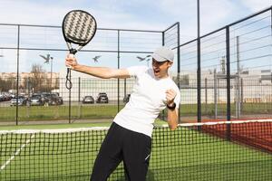 Europese Mens Holding padel racket in hand- en klaar naar terugkeer bal terwijl spelen in rechtbank foto