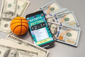 smartphone met het gokken mobiel toepassing en basketbal bal met geld detailopname. sport en wedden concept foto