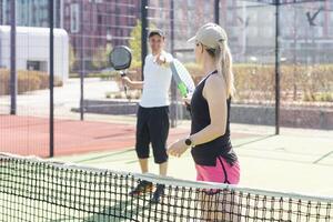 jong vrouw spelen padel tennis met partner in de Open lucht tennis rechtbank foto