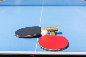 rood en zwart tafel tennis peddels en bal Aan de blauw tafel tennis tafel met netto. ping pong concept met kopiëren ruimte foto