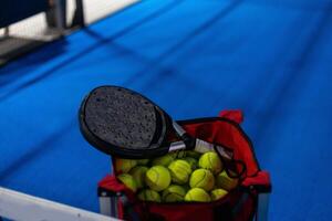 peddelen tennis racket en ballen Aan de blauw peddelen rechtbank foto