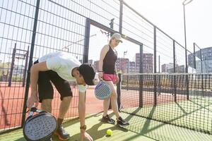 sport- paar met padel rackets poseren Aan tennis rechtbank foto