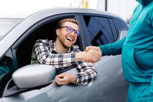 Mens buying auto en beven handen met verkoper tegen wazig auto, detailopname. concept van kiezen en buying nieuw auto Bij toonzaal foto