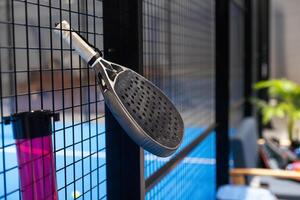 zwart professioneel peddelen tennis racket en bal met natuurlijk verlichting Aan blauw achtergrond. horizontaal sport thema poster, groet kaarten, koppen, website en app foto
